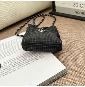 Dettaglio di una mini borsa a tracolla a quadretti stile giapponese su un libro