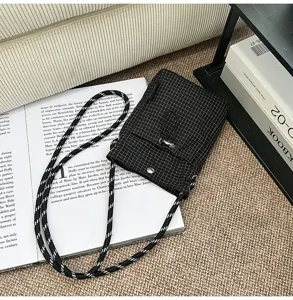 Dettaglio di una borsa a tracolla nera a quadretti su uno sfondo lifestyle.