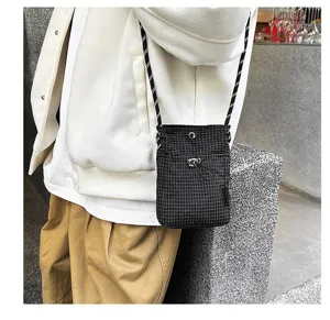 Primo piano di una borsa a tracolla per cellulare leggera a scacchi neri all'aperto