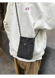 Primo piano di una piccola borsa a tracolla per cellulare a quadretti bianchi e neri