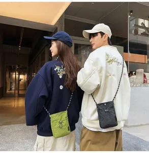 Coppia che indossa pochette porta cellulare leggere in verde e con motivo a scacchi.