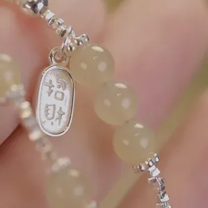 Détail macro d'un bracelet de cheville avec breloque en argent gravée porte-bonheur