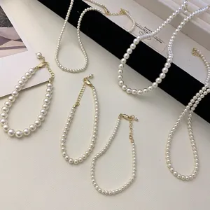 Detailed view of minimalist white pearl necklaces and bracelets with gold clasps