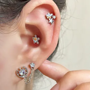 Close-up of sparkling star and moon themed ear piercings and studs on a human ear
