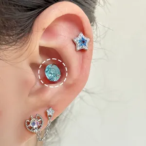Close-up detail of a sparkling light blue crystal conch piercing on a woman's ear.