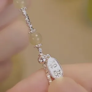 Détail d'un bracelet de cheville vintage en perles d'argent avec un pendentif porte-bonheur.