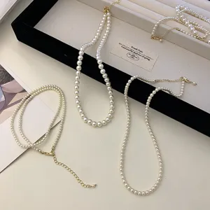 Detail view of white pearl necklaces with gold-tone lobster clasps and extension chains.