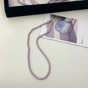 Detail shot of an elegant purple pearl necklace on a minimalist card background.