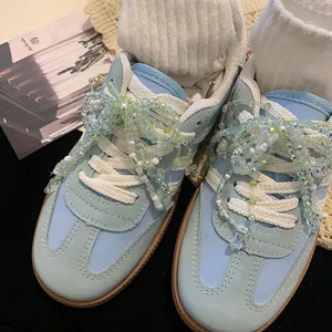 Vue détaillée des bijoux de chaussures en perles sur baskets bleu clair.