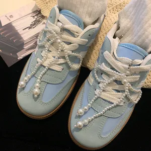 Vue détaillée de charmants nœuds en perles blanches fixés sur des lacets de baskets bleues.