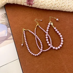 Set of three purple pearl necklaces with elegant gold-tone clasps and extension chains