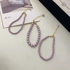 Macro view of three elegant purple pearl necklaces featuring golden lobster clasps