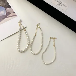 Collection of minimalist white pearl necklaces with gold clasps in varying pearl sizes.