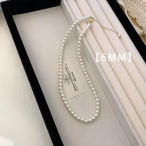 Macro view of a 6mm minimalist white pearl necklace presented in a jewelry box tray.