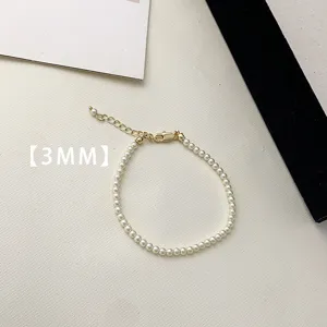 Detail view of a 3mm white pearl bracelet with gold-tone extension chain and clasp