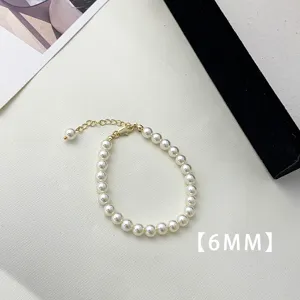 Macro view of 6mm white pearls and gold-plated extender chain on a minimalist bracelet.