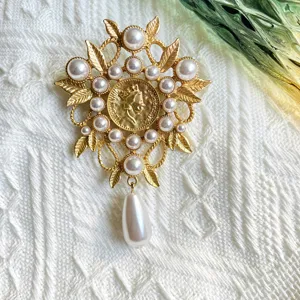 Detailed view of a vintage baroque matte gold brooch featuring pearls and a portrait design.