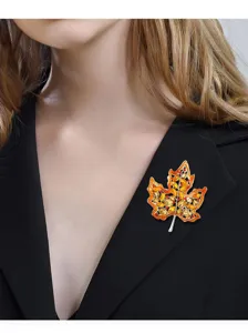 Primer plano de un broche de hoja de arce en esmalte naranja sobre la solapa de un traje