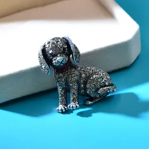 Dettaglio di una spilla a forma di cucciolo con strass trasparenti e rossi brillanti.