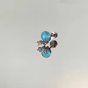 Dreamy blue planet stud earring with sparkling star stones on a reflective mirror