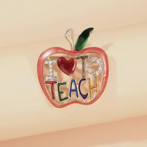 Detail shot of a colorful apple brooch featuring "I Love To Teach" text and rhinestones.