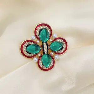 Gros plan détaillé d'une broche vintage de style cour avec du verre vert et des perles