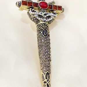 Close-up of a retro sword brooch with intricate rhinestone and red stone inlay