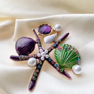 Macro view of an elegant purple starfish and green shell brooch with pearls and rhinestones
