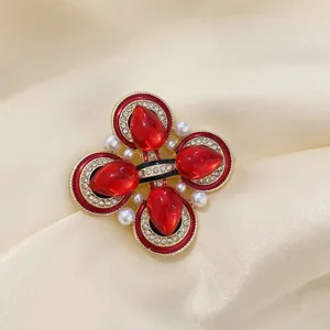 Gros plan d'une broche croix style cour vintage avec pierres rouges et perles blanches