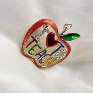 Detailed macro view of colorful apple brooch with 'I Love Teach' crystal engraving