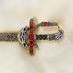 Detailed macro view of a vintage rhinestone sword brooch pin featuring red crystals