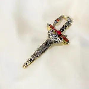 Detailed macro view of a vintage rhinestone dagger brooch pin with red gemstones