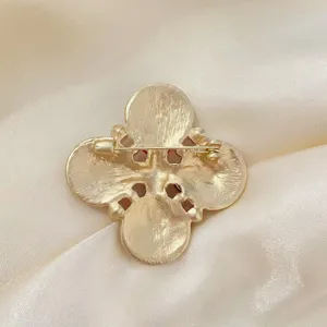 Vue détaillée du dos d'une broche croix vintage dorée avec fermoir épingle
