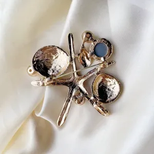 Back view of gold starfish and seashell brooch on white silk background