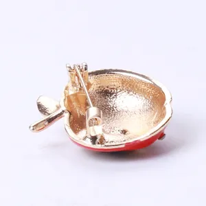 Back view of a gold-toned apple brooch showing the secure safety pin clasp mechanism.