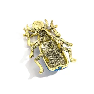 Achterkant van vintage keverspeld met getextureerde gouden afwerking en veilige sluiting