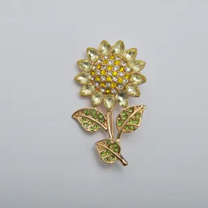 Detailed macro view of a vintage gold-toned sunflower brooch with yellow and green crystals.