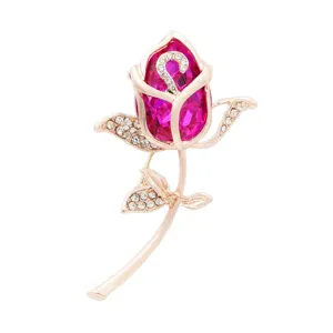 Close-up of rose gold brooch with faceted magenta crystal and sparkling rhinestones