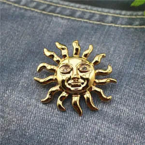 Gros plan d'une broche vintage soleil doré avec yeux en strass sur fond de denim.