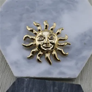 Gros plan d'une broche soleil dorée vintage avec des yeux en strass sur une base en marbre