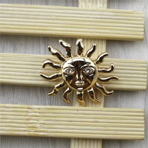 Vue détaillée d'une broche soleil dorée vintage avec un visage et des yeux en cristal