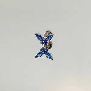 Close-up of blue butterfly stud earring with sparkling gemstones on reflective surface