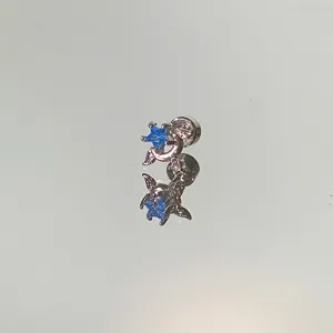Close-up of a silver stud earring featuring a blue star and diamond crescent moon.