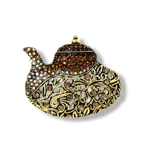 Detailansicht einer goldenen Teekannen-Brosche mit braunen Glitzersteinen
