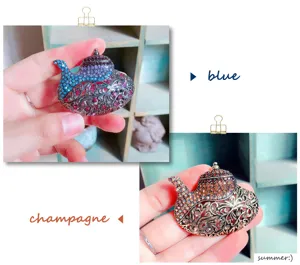 Detail exotischer Teekannen-Brosche mit bunten Strasssteinen in Blau und Champagner