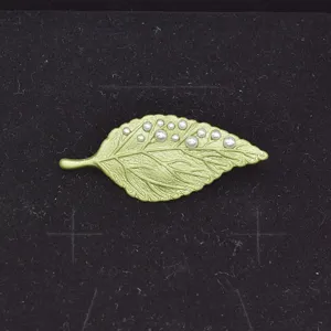 Primer plano detallado de un broche de hoja de esmalte verde vintage con perlas