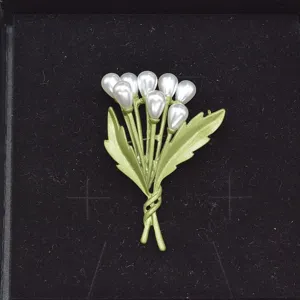 Primer plano de un broche vintage de laca verde con elegantes cuentas de perlas.