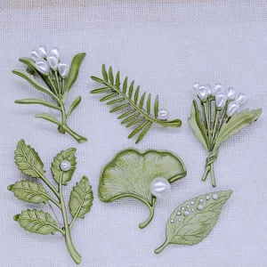 Vista detallada de seis broches vintage de esmalte verde con hojas, flores y perlas
