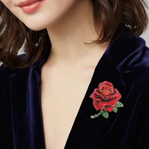 Eleganter roter Rosen-Broschen-Anstecker mit funkelnden Kristallen auf einer Samtjacke