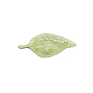 Elegante broche vintage de hoja verde con detalles de perlas sobre fondo blanco